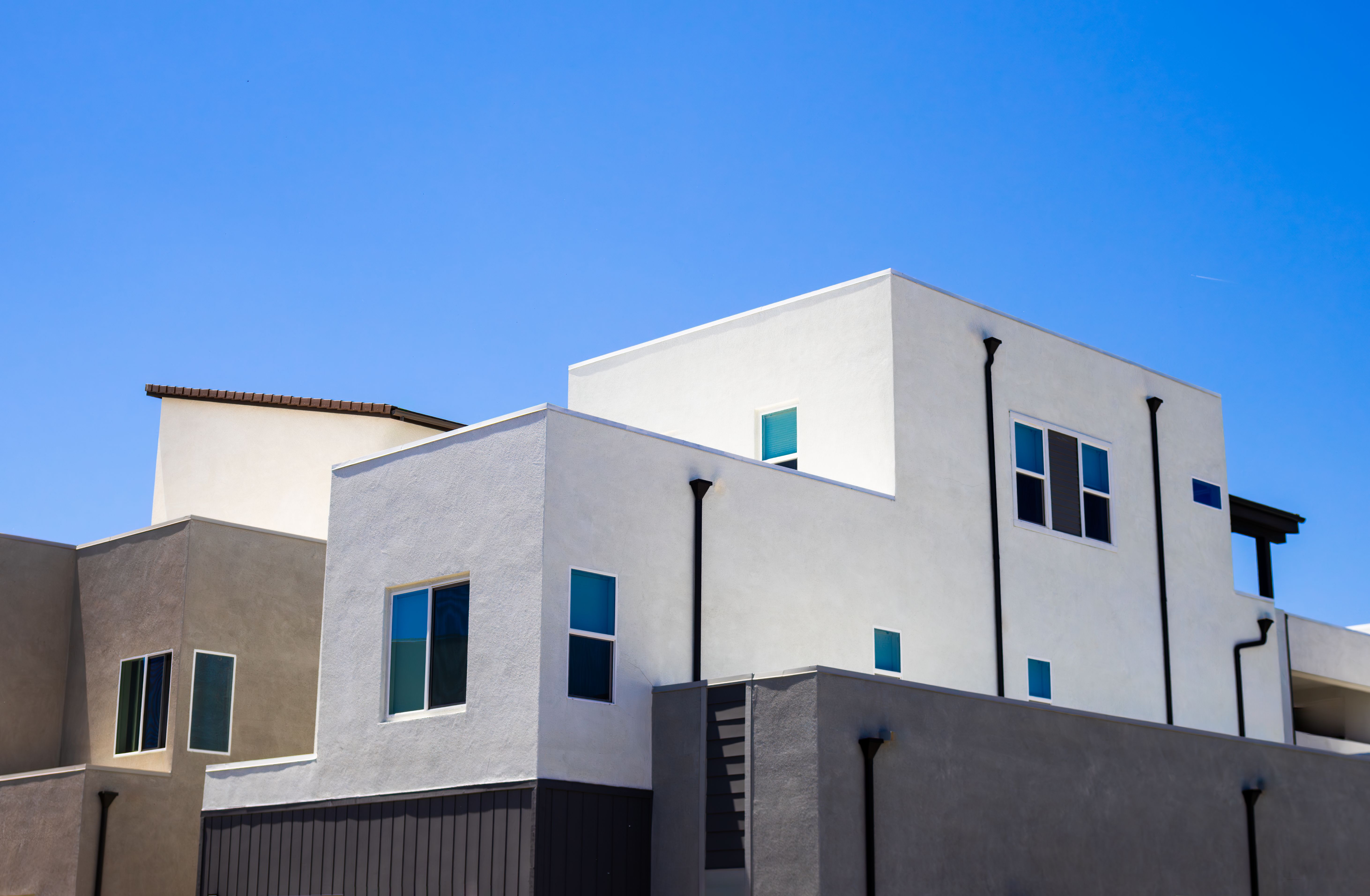 Illustrative modern apartment building exterior with balconies under a bright sky.